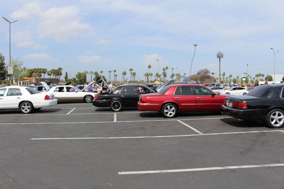 Row of white, black and red full-size sedans parked at an outdoor car meet