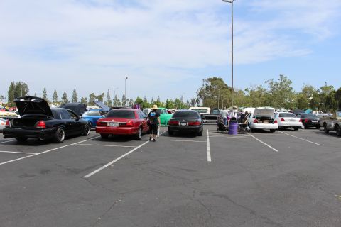 Black, red and silver sedans with open trunks across an empty parking lot