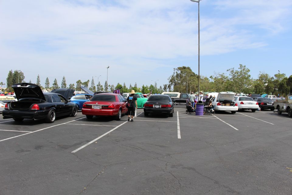 Black, red and silver sedans with open trunks across an empty parking lot