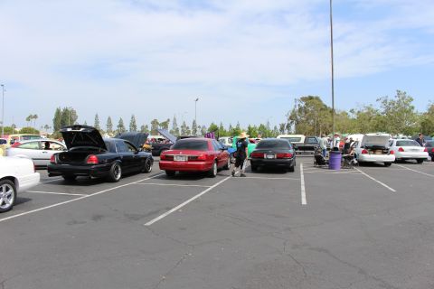 Black and red sedans with open trunks parked across a wide asphalt lot