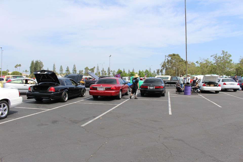 Black and red sedans with open trunks parked across a wide asphalt lot