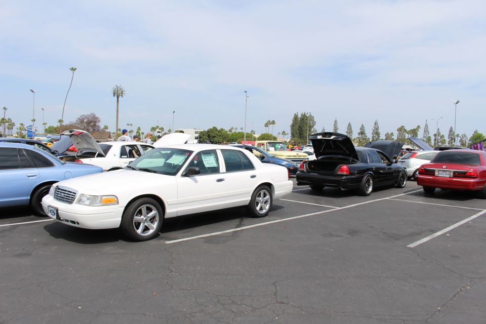 White sedan beside a black sedan with open trunk in a sunny parking lot
