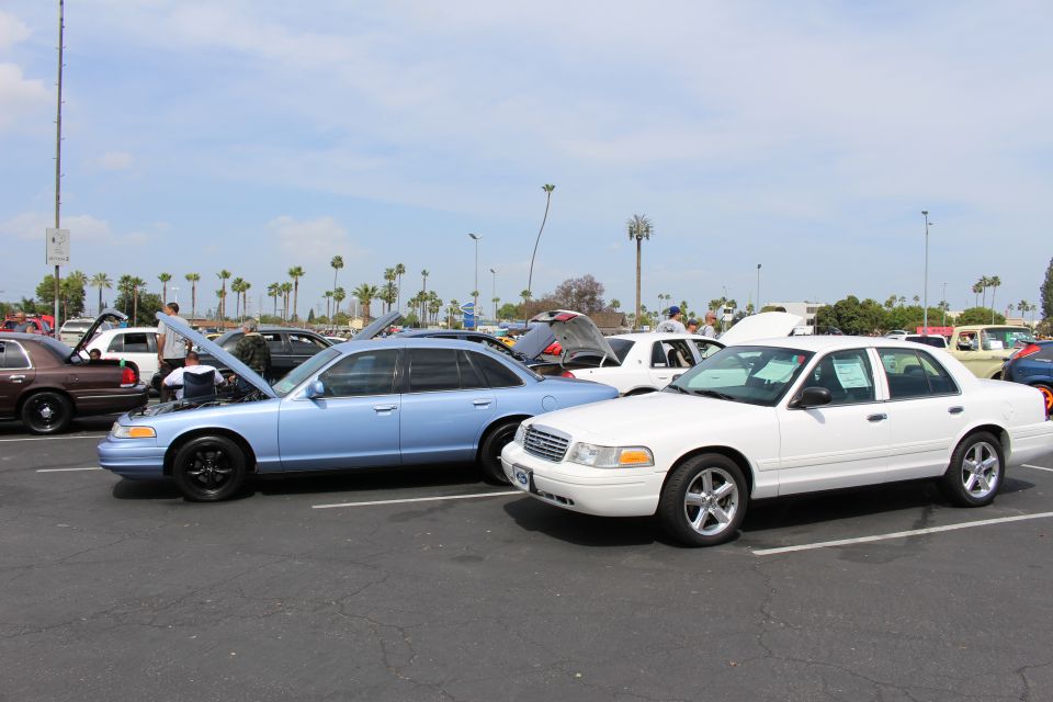 Light-blue sedan with open hood beside a white sedan in a parking lot