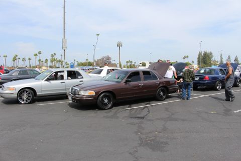 Brown and silver sedans with people standing nearby in a parking lot