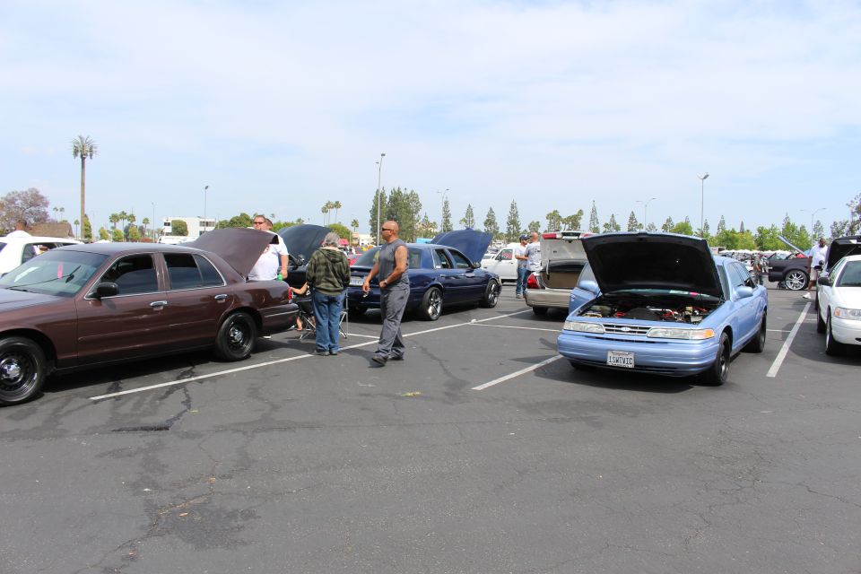 Brown sedan and blue car with open hood, people gathered in a lot