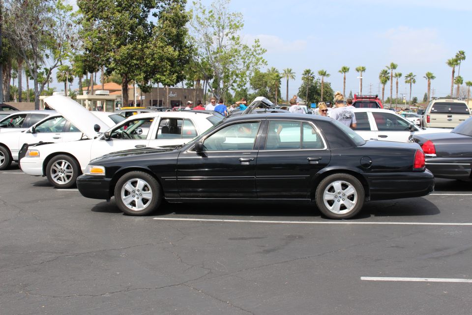 Black full-size four-door sedan shown in profile in a parking lot with other sedans behind it
