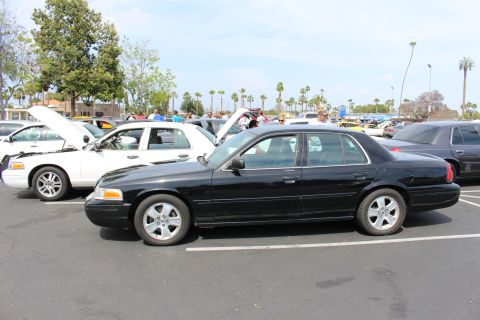 Black full-size sedan in profile parked among white and dark sedans in a lot