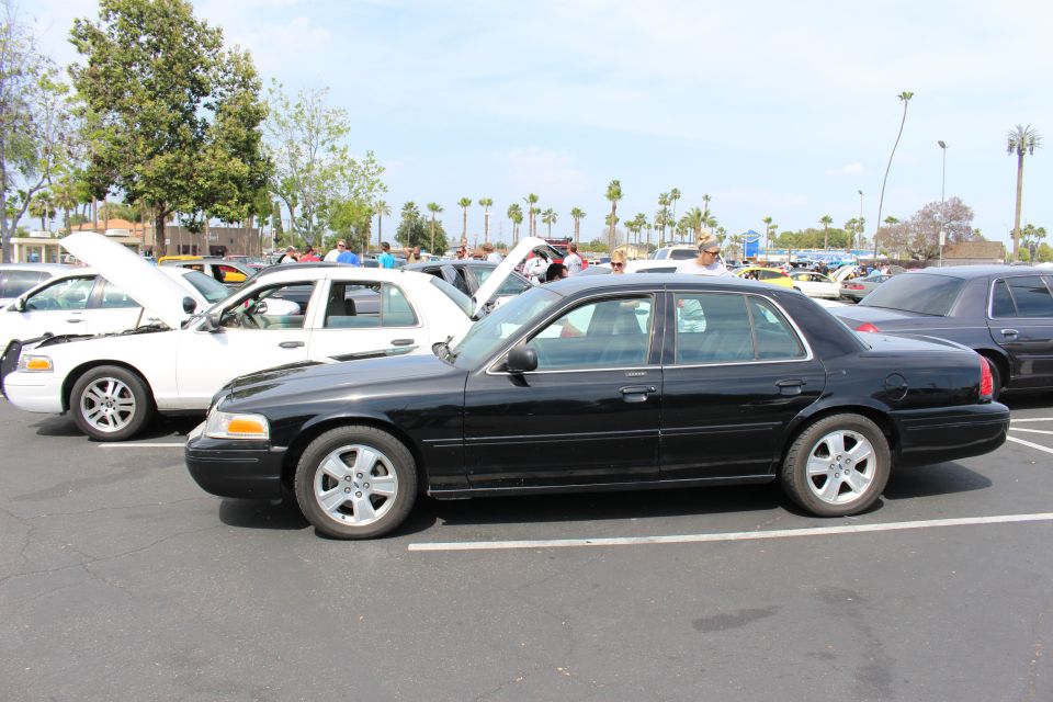 Black full-size sedan in profile parked among white and dark sedans in a lot