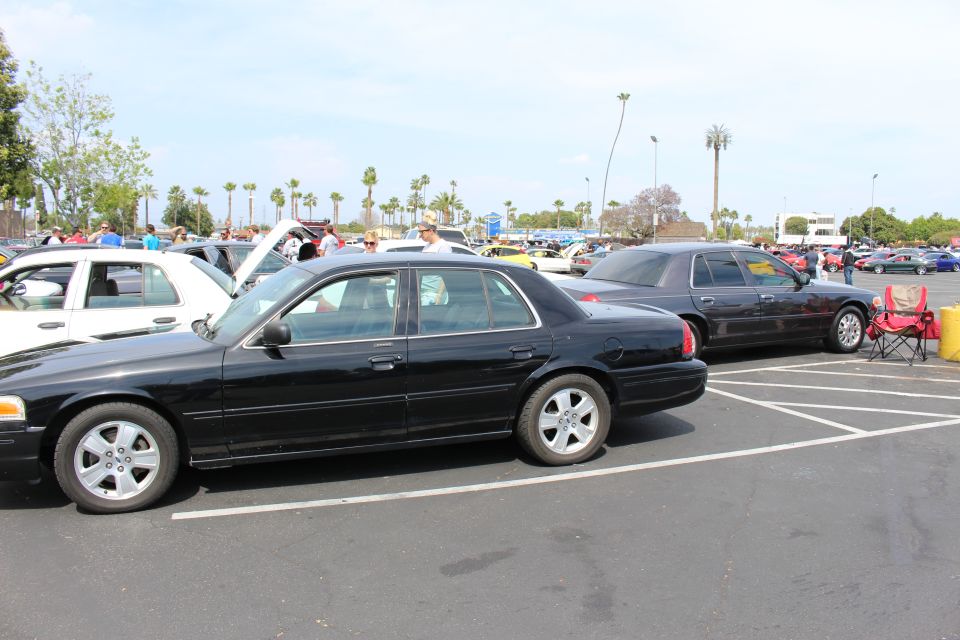Black sedans parked in marked spaces with a red folding chair and crowd in the background