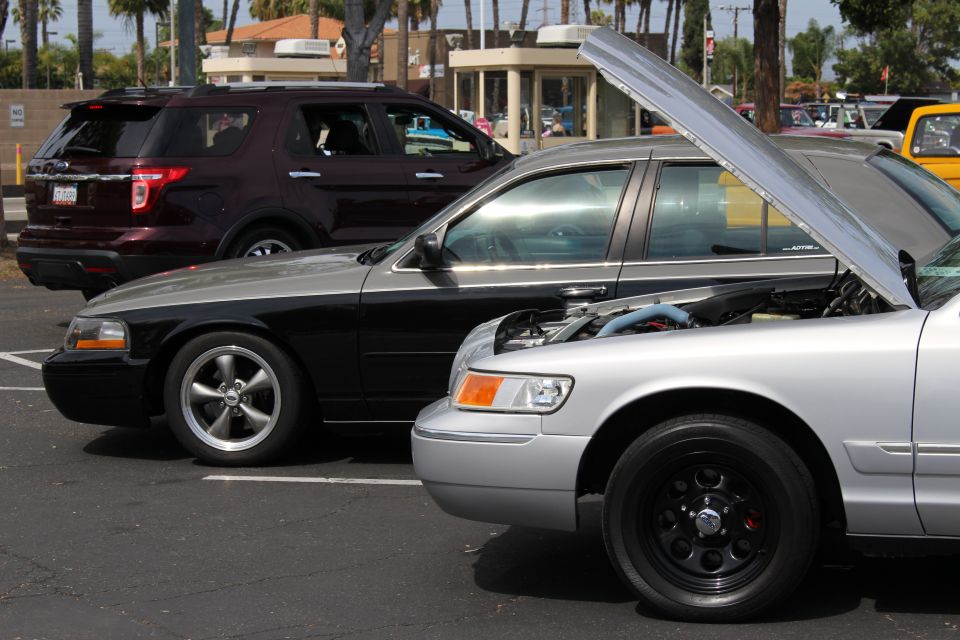 Black sedan and silver sedan with open hood and black steel wheels parked beside a dark SUV