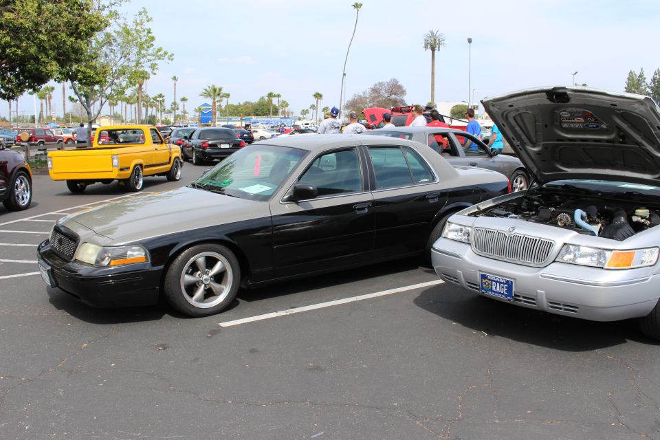 Black sedan beside a silver sedan with raised hood, yellow pickup and cars in background