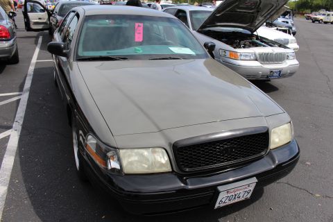 Gray full-size sedan with pink windshield placard parked nose-out at a car show