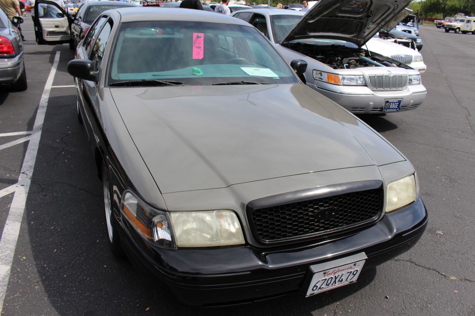 Gray full-size sedan with pink windshield placard parked nose-out at a car show
