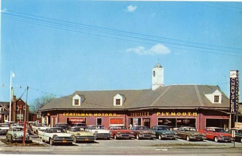 1991 Ford LTD Crown Victoria - A vintage postcard shows a Chrysler Plymouth dealership with several classic cars on display.