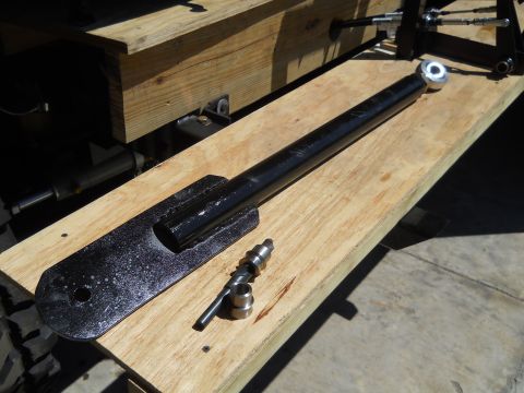 1992 Ford Bronco - A black metal suspension component and associated hardware are laid out on wooden planks.