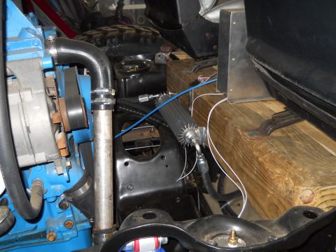 1992 Ford Bronco - Close-up view of engine bay components, including an oil cooler and blue-painted engine block, with wooden supports in the background.