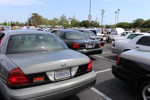 Gray Ford sedan rear view with California plate 6UVV656 among rows of cars at a meet