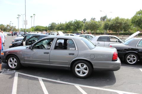 Side view of a gray Ford Crown Victoria sedan parked at an outdoor car meet