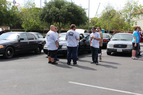 Men talking beside black and white Ford sedans at an outdoor meet