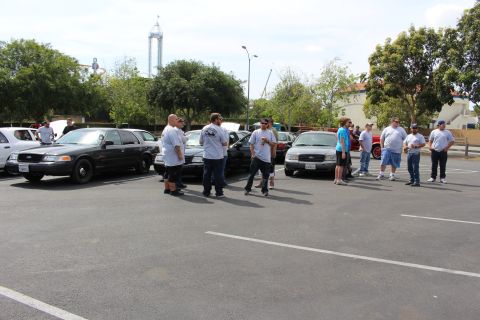 People standing in a parking lot lined with black and white sedans
