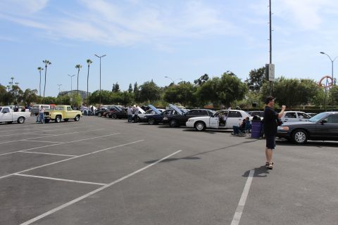 Wide view of a parking-lot car show with sedans and a vintage pickup truck