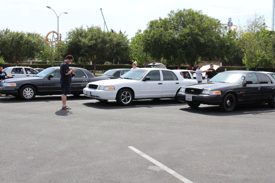 Black, white and gray sedans parked at an outdoor car meet, person on phone