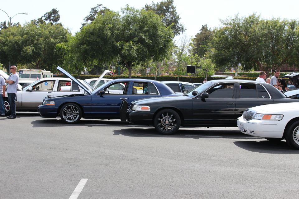 Lowered blue and black Ford sedans with aftermarket wheels at a car meet