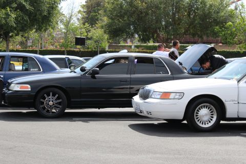 Black sedan with chrome wheels beside a white Mercury Grand Marquis