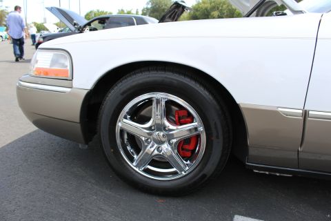 Front fender and chrome wheel of a white two-tone sedan at a car show