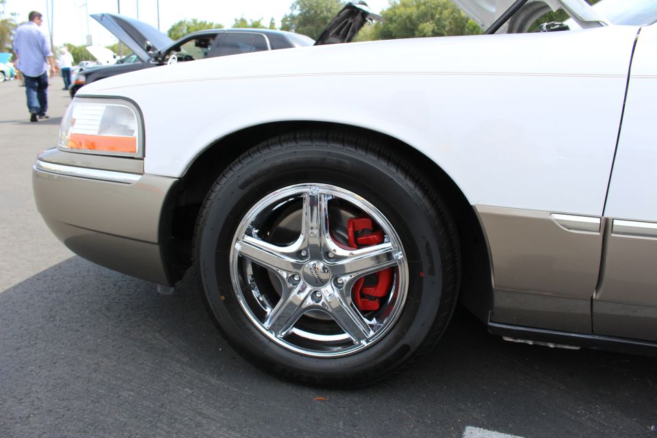 Front fender and chrome wheel of a white two-tone sedan at a car show