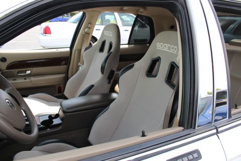 Interior of a sedan fitted with gray Sparco bucket seats and a wood-trim dash