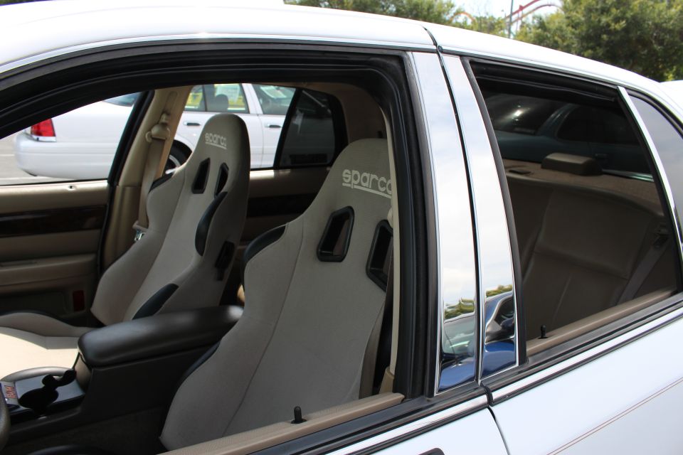 Gray Sparco bucket seats seen through the open window of a white sedan