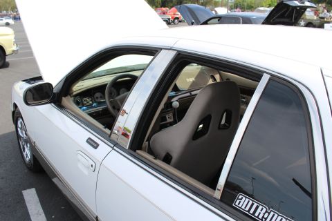 Black Sparco bucket seat visible through the open window of a white sedan