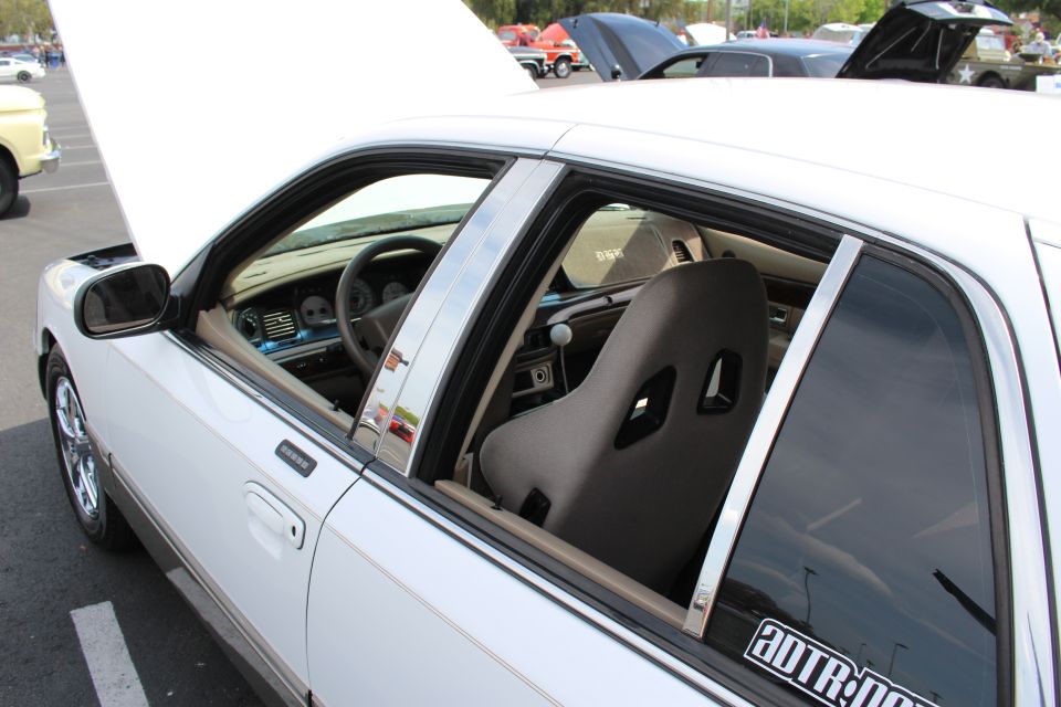 Black Sparco bucket seat visible through the open window of a white sedan
