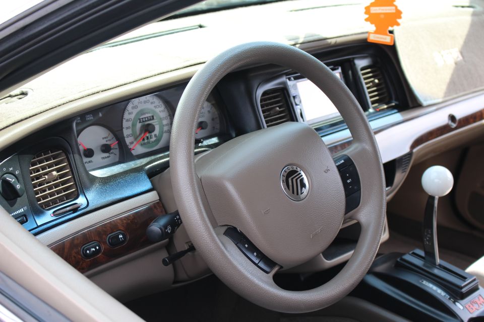 Mercury steering wheel, tan gauges and white-ball shifter in a sedan interior