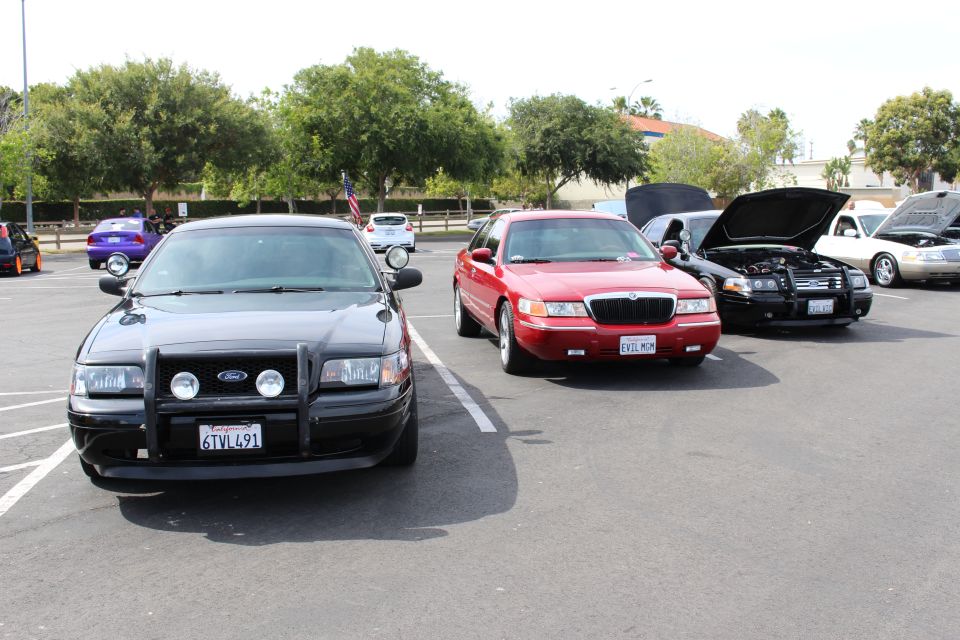 Row of full-size sedans at a show: black Ford, red Mercury and others