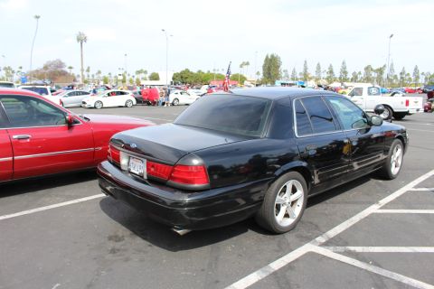 Rear three-quarter view of a black Ford sedan with chrome wheels in a parking lot