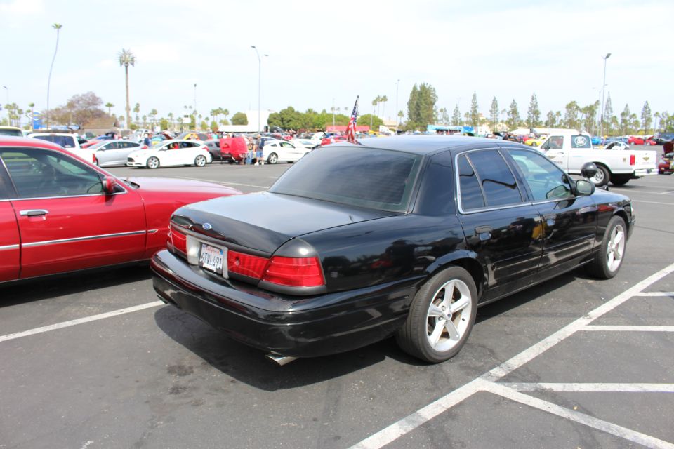 Rear three-quarter view of a black Ford sedan with chrome wheels in a parking lot