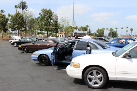Row of sedans angled into parking spaces, including light blue and white cars