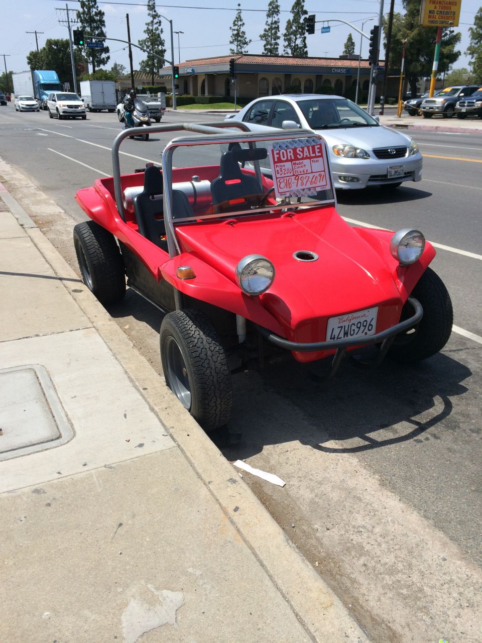 Red dune buggy parked on curb, with a "FOR SALE" sign on windshield