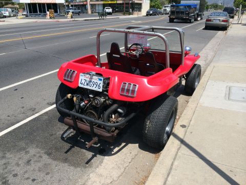 1968 Ford Mustang - A bright red dune buggy with a roll cage is parked on the side of a street, its rear engine exposed.