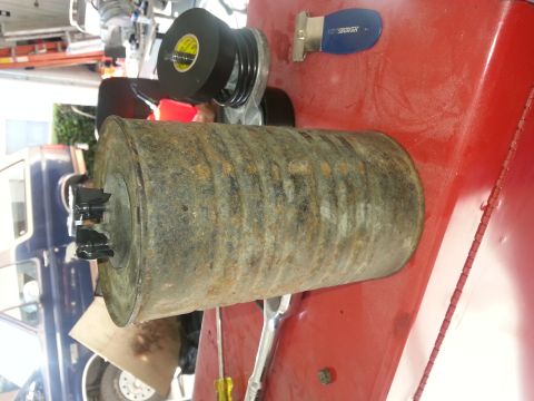1994 Ford Bronco - A rusty exhaust pipe sits on a red surface next to tools and a roll of tape, with a blue vehicle in the background.