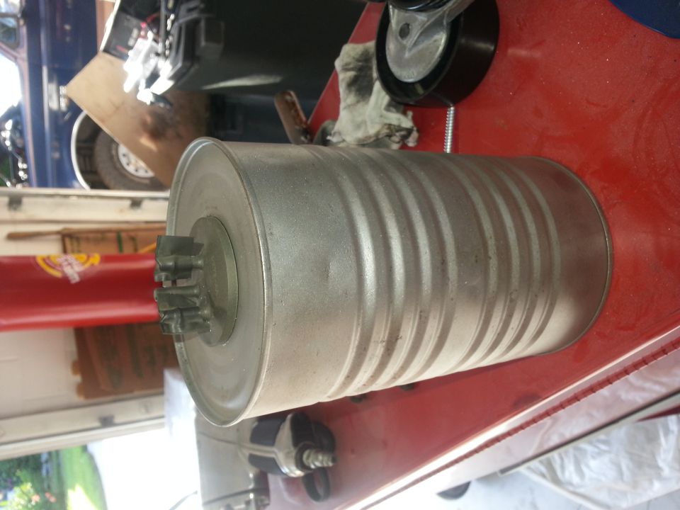 Exhaust muffler with splined shaft on one end, resting on a red surface