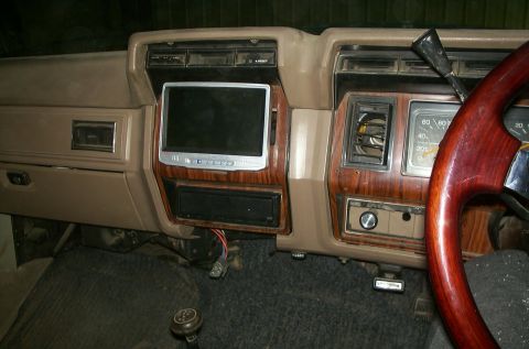 1981 Ford Bronco - The dashboard shows a wood grain finish and an aftermarket screen, with a wooden steering wheel visible.
