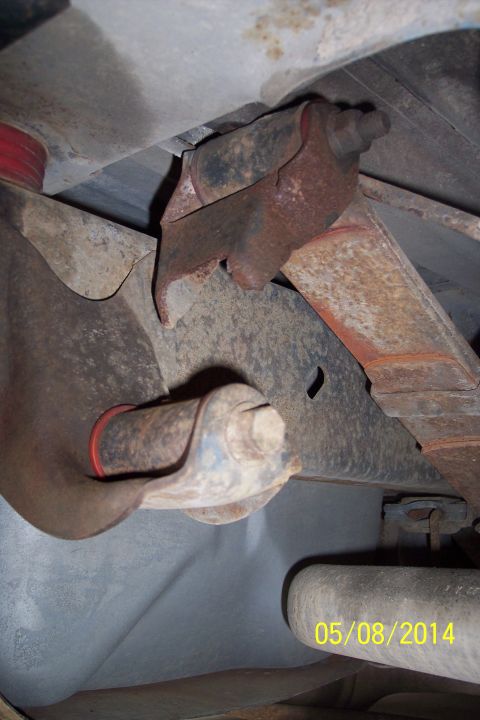 1978 Ford Bronco - Underside view of vehicle suspension parts, showing rust and wear on the leaf spring and bracket.