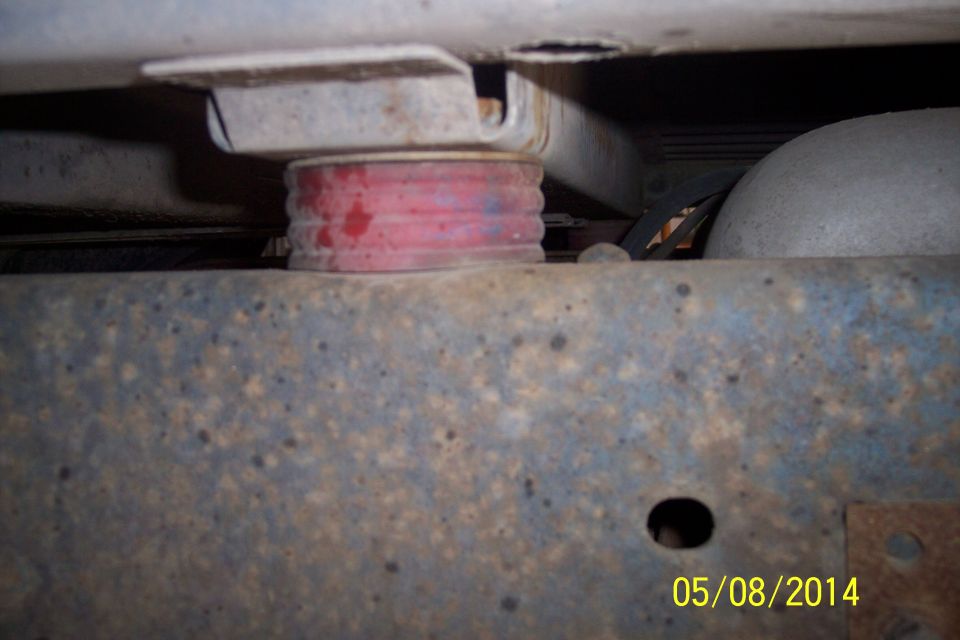 Close-up of a red suspension bushing mounted on a rusty vehicle frame