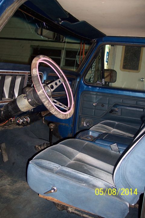 1978 Ford Bronco - The interior of a blue 1978 Ford Bronco shows velour seats and a patterned steering wheel.