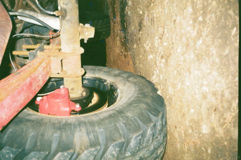 1979 Ford Bronco - Close-up view of a rear disc brake assembly, likely from an older vehicle, with a red caliper and a large tire visible.