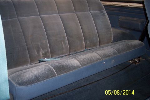 1978 Ford Bronco - The interior of a vehicle shows a blue velour bench seat with a seatbelt visible.