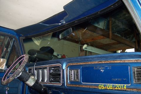 1978 Ford Bronco - The dashboard and interior of a blue pickup truck, with a shelf installed above the windshield.